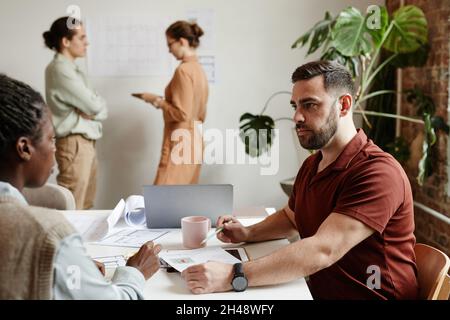 Side view portrait of bearded man at meeting with creative design team, copy space Stock Photo