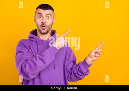 Portrait of attractive cheerful amazed guy demonstrating ad copy blank space isolated over bright yellow color background Stock Photo