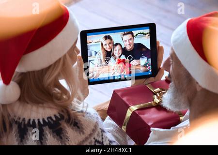 Happy grandparents old couple greeting family on Christmas video call. Stock Photo