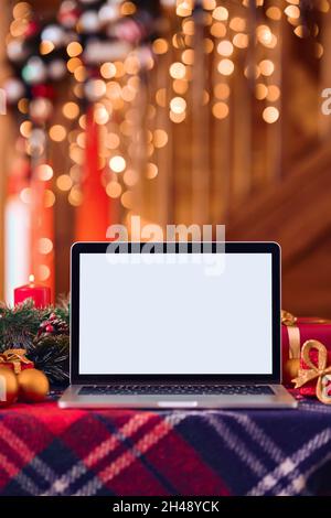 Laptop computer mockup white blank screen on Christmas table background. Stock Photo