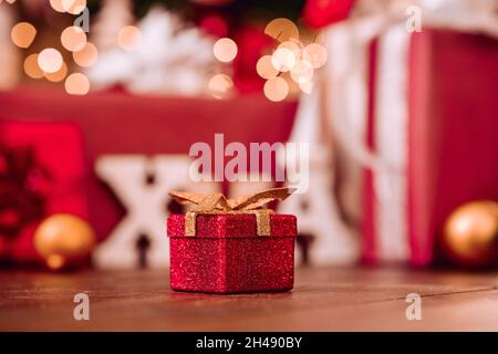 Small red Xmas present gift box under Christmas tree background. Stock Photo