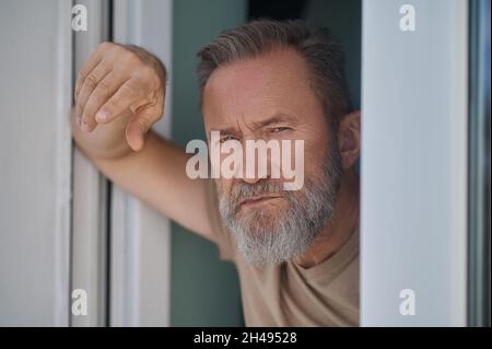 Despondent mature person standing by the window Stock Photo