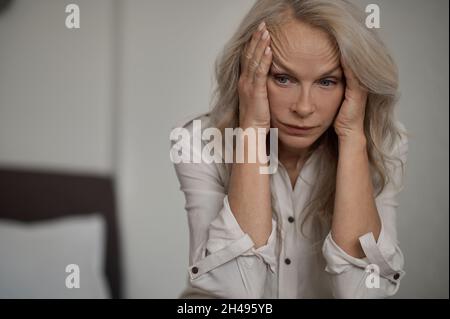 Despondent blonde mature woman suffering from loneliness Stock Photo
