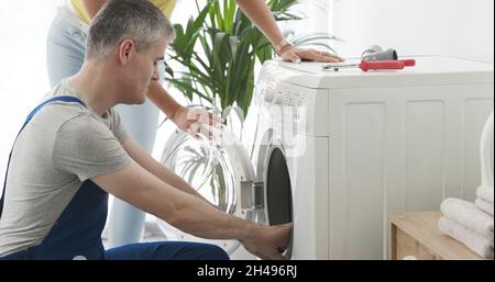 Technician repairing a washing machine at home, he is checking the gasket Stock Photo