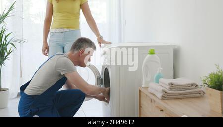 Technician repairing a washing machine at home, he is checking the gasket Stock Photo