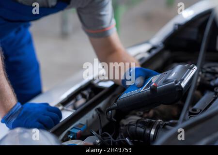 Professional mechanic doing a car inspection, he is using a battery tester Stock Photo