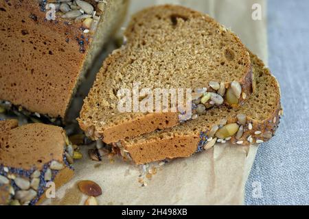 Cereal bread on a tablecloth close-up. Yeast-free bread made with rye flour. Triangular bread with poppy seeds and sunflower seeds. Stock Photo