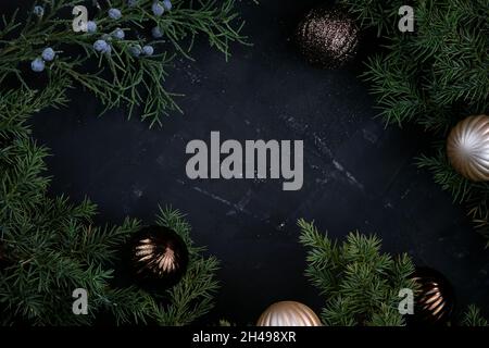Beautiful Christmas background top view. Coniferous twigs on a black background. Christmas tree balls and juniper twigs. Stylish New Year theme Stock Photo