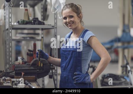 Professional confident female mechanic working in the garage, she is using a bench vise Stock Photo
