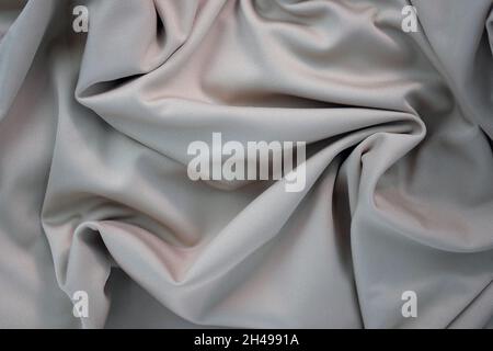 Draped canvas close-up. Abstract polyester fabric background. Top view of fabric with many folds. waves of satin material, shiny texture. Stock Photo