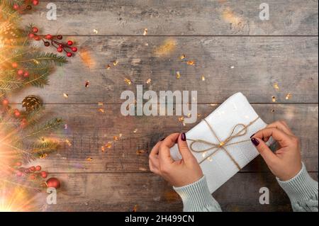 Christmas and New Year concept. Womans hands open gift or present box decorated confetti on wooden table. top view. Flat lay composition for Christmas Stock Photo