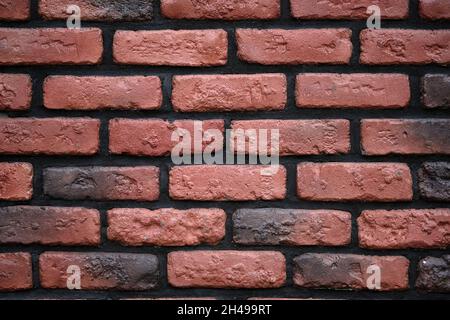 Red brick wall with black seams background. Decorative wall with brown tiles and black cement. Brick wall texture close-up. Stock Photo