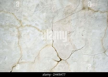 White wall with cracks close-up. Wall texture of an old building. Stone wall with cracks on the background surface. Stock Photo