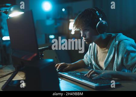 Cool teenager wearing headphones and playing online video games, gaming and entertainment concept Stock Photo