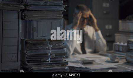 Stressed businessman working until late and having a headache Stock Photo