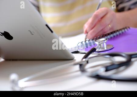 doctor using ipad tablet computer and writing pad, norfolk, england Stock Photo
