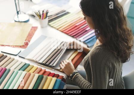 Young interior designer sitting at desk and choosing fabric samples for her project Stock Photo