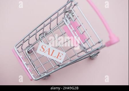 the word sale on a white paper in a miniature shopping cart Stock Photo