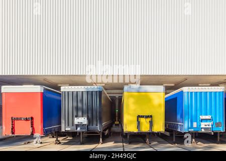 Red, black, yellow and blue truck trailers in front of the loading dock of a Dutch warehouse Stock Photo