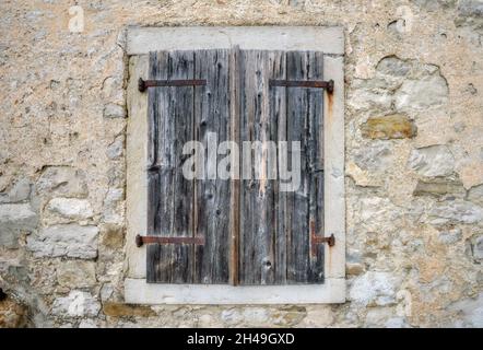 Close-up of a window with wooden shutters on stone wall of old house. Hum, Croatia Stock Photo