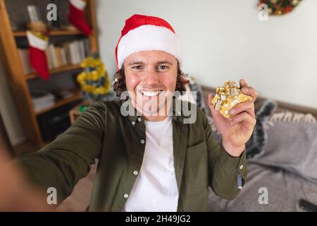 Portrait of caucasian disabled man wearing a santa hat holding christmas gift at home Stock Photo