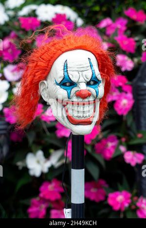 A Halloween yard decoration - a scary looking clown figure in front of flowers. In Queens, New York City. Stock Photo