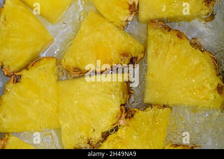 Slices of pineapple in water on white background. Pineapple close-up in liquid with bubbles. Slices of ripe pineapple in water. Macro image of fruits Stock Photo