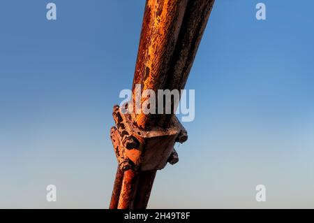 A fragment of a rusty steel rope in the fastening of the bridge span against the background of a blue sky Stock Photo