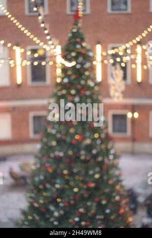 Christmas tree with glowing lights. Old town with pine decorated with garlands, blurred bokeh view Stock Photo