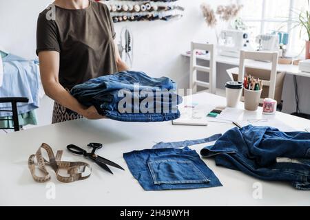 Denim Upcycling Ideas, Using Old Jeans, Repurposing Jeans, Reusing Old Jeans, Upcycle Stuff. Woman seamstress holding Stack of old blue jeans in Stock Photo
