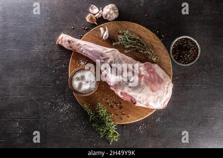 Raw lamb leg with spices, salt, herbs and garlic - top of view. Stock Photo