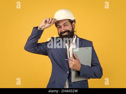 Architect in hardhat holding blueprints and greeting by touching helmet, welcome on board Stock Photo