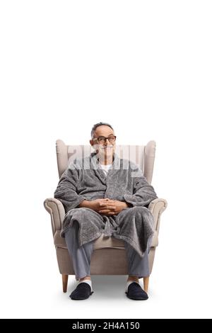 Mature man in a bathrobe and pajamas sitting in an armchair isolated on white background Stock Photo