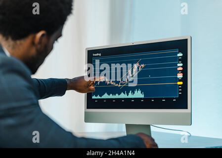 Black man analyzing financial diagrams on binary option Stock Photo