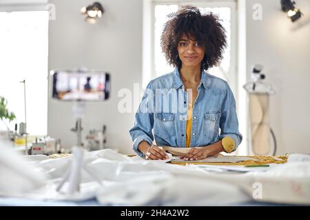 African-American woman designer shoots video for blog at cutting table with tools Stock Photo