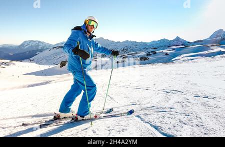 Expert skier on blue uniform on relax moment at french alps ski resort - Winter adventure and sport concept with professional guy on mountain top Stock Photo