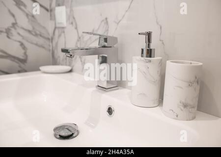 Close up of a white sink with marble set for the bathroom standing in a white bathroom. Stock Photo