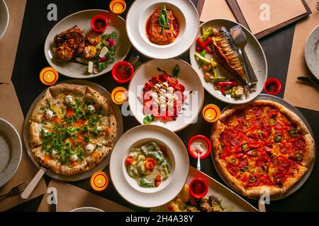 Top down view on enormous buffet of delicious freshly prepared european cuisine and pizza with empty paper for menu Stock Photo