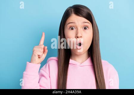 Photo of childish impressed schoolgirl dressed pink outfit pointing finger empty space copyspace isolated blue color background Stock Photo