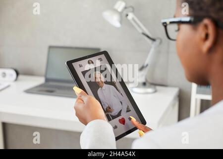 Woman on dating site or in application presses red heart as sign of sympathy for handsome man. Stock Photo