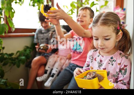 Four children holding their favorite pets on hands. Kids playing with hamster,turtle at home. Stock Photo