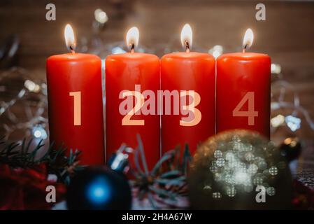 Four numbered red advent candles with three candles lit and christmas decoration lying in snow as template Stock Photo