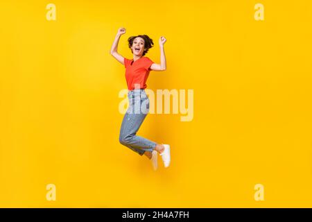 Full size profile photo of hooray nice brunette lady jump wear orange t-shirt isolated on yellow background Stock Photo