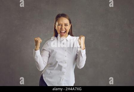 Joyful woman clenched her fists, excited by the great news or celebrating important achievements. Stock Photo