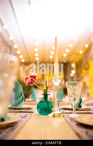 a flower in a turquoise vase on the table in the interior. Stock Photo