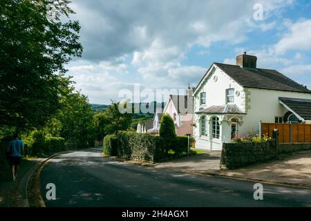 Sleights Moor hill climb out of Grosmont village with pretty pastel coloured houses lining the road and a person walking down to the village, North Yo Stock Photo