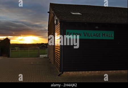As dusk falls on 22nd of October 2021 the setting sun high lights the wooden side of the village hall at Ecton in Northamptonshire. Stock Photo