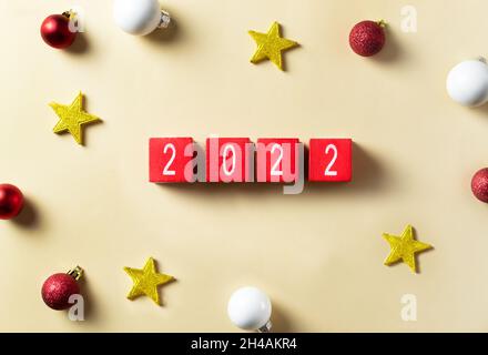 Greeting card Happy New Year 2022. Wooden cubes of red color with numbers of the coming year. Celebration atmosphere. Top view.