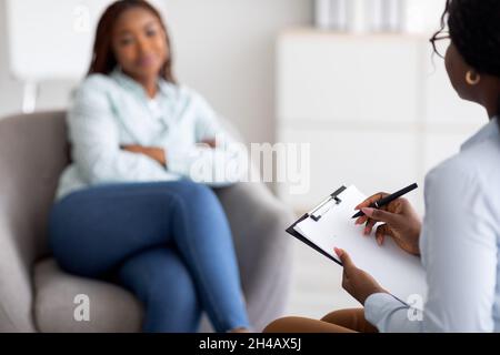 Young black lady receiving professional psychological help at office, selective focus. African American psychotherapist having session with millennial Stock Photo