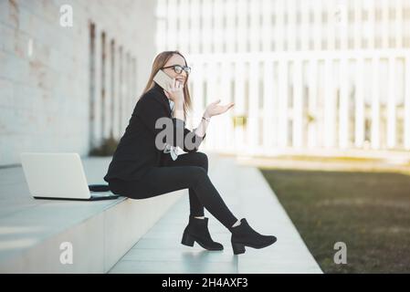 Busy young business woman talking on her mobile phone Stock Photo